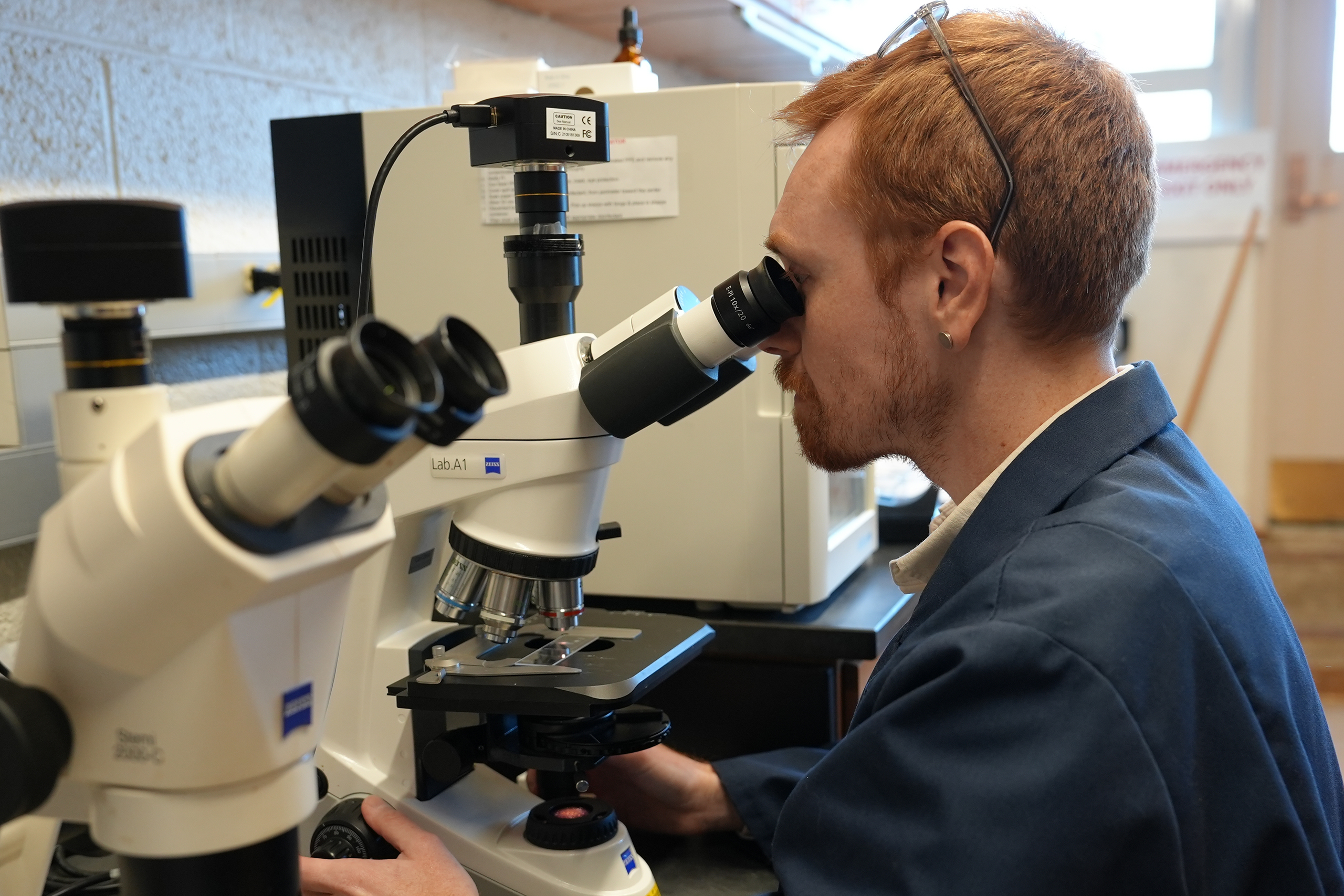 researcher looking through a microscope