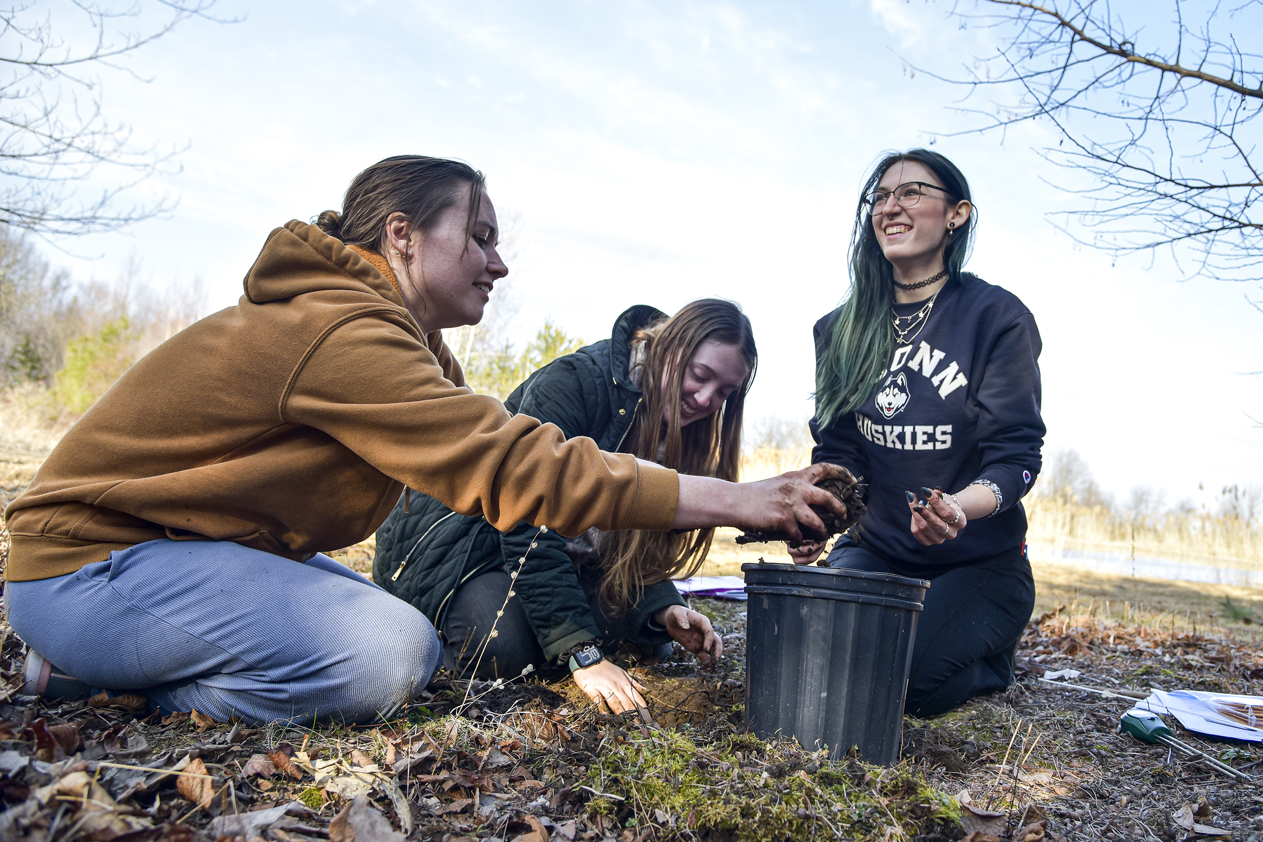 students outside in a field transferring soil into a bucket