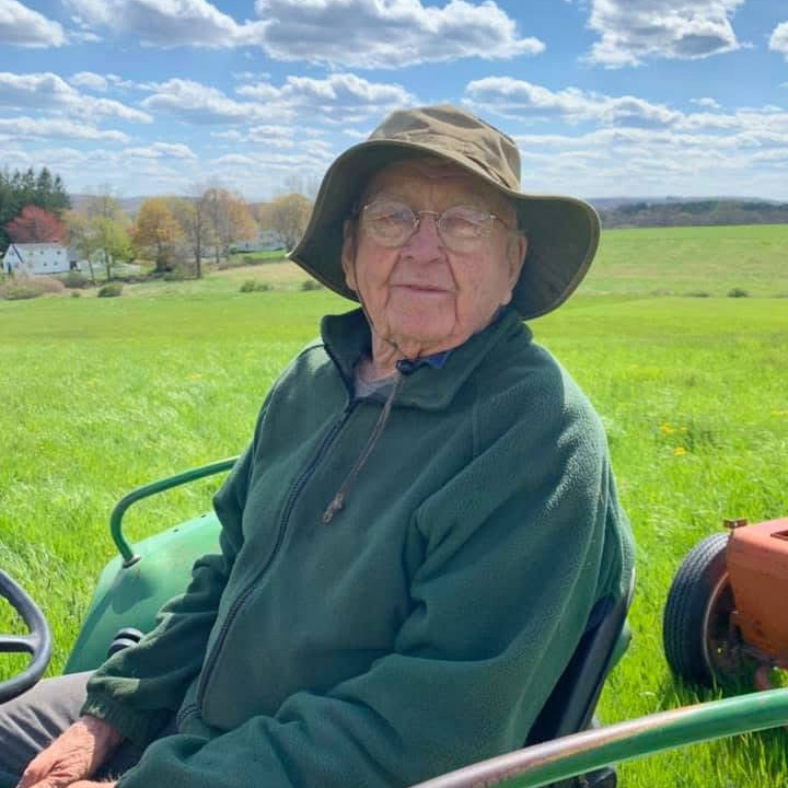 George Leigh Minor sitting on a tractor outdoors on his farm
